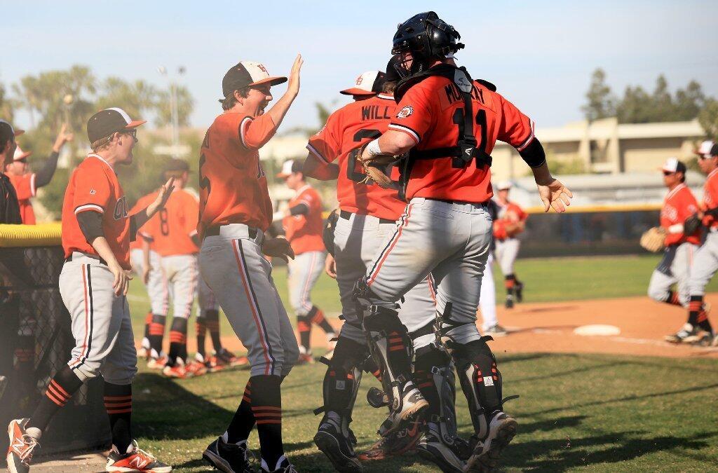 Huntington Beach High catcher Tyler Murray (11) celebrates with teammates after the Oilers completed a triple play to close out the fourth inning against Newport Harbor in a Sunset League game on Tuesday.