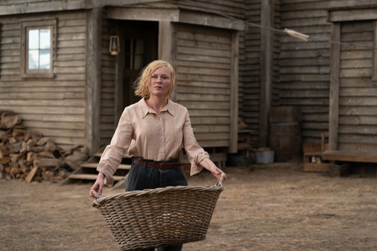 A woman in the old West holds a wicker laundry basket