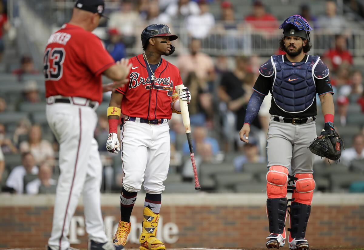 Atlanta Braves' Ronald Acuna Jr., center, looks toward the pitcher's mound at Miami Marlins pitcher Pablo Lopez (not shown) after being hit by the first pitch thrown by Lopez in the first inning of a baseball game Friday, July 2, 2021, in Atlanta. Braves manager Brian Snitker, left, and Marlins' catcher Jorge Alfaro, right, look on. (AP Photo/Ben Margot)