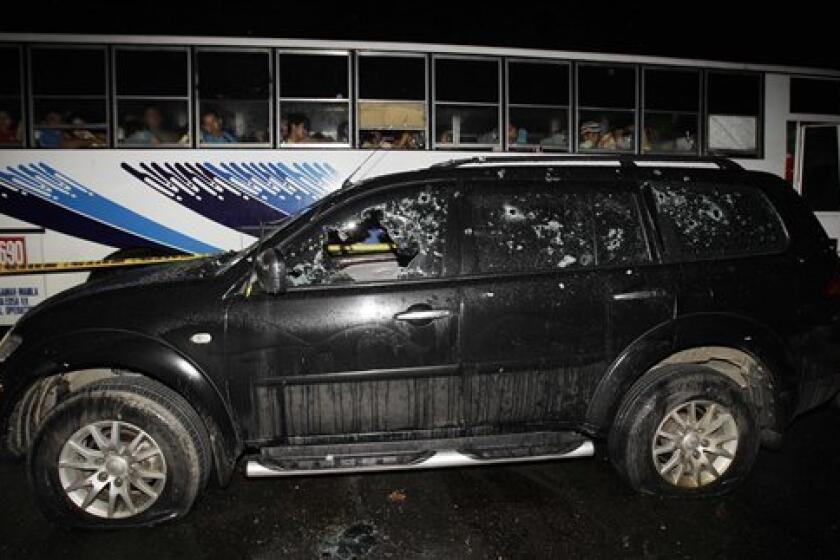 Passengers look at the bullet-riddled vehicle of suspected criminals along a road in the town of Atimonan in Quezon province, about 140 kilometers (100 miles) southeast of Manila, Philippines late Sunday Jan. 6, 2013. Philippine army special forces and police killed 13 suspected criminals in a gunbattle Sunday in the latest violence to erupt in the country in the past week. (AP Photo/Aaron Favila)