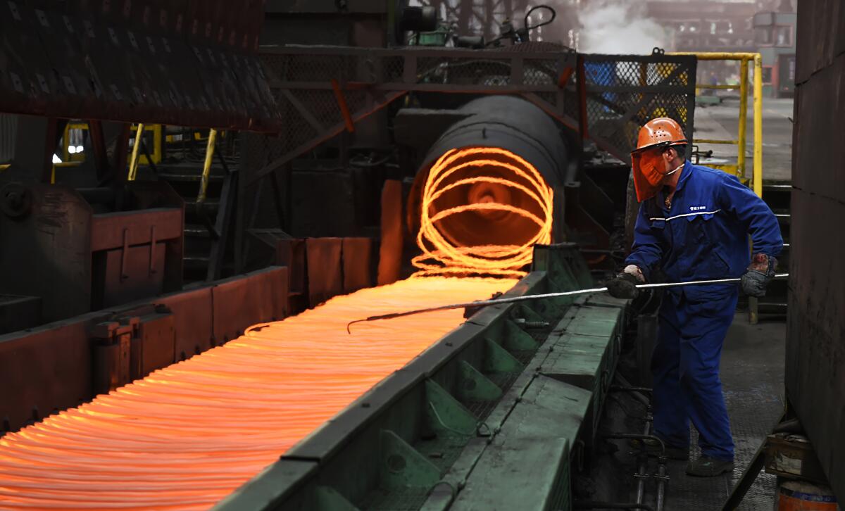 A worker manipulates coils of steel at Xiwang Special Steel in Zouping County in eastern China's Shandong province.