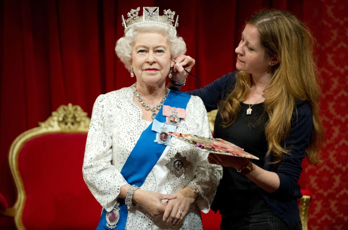 A waxwork figure of Britain's Queen Elizabeth II at Madame Tussauds in London gets a touchup from painter Lisa Burton.