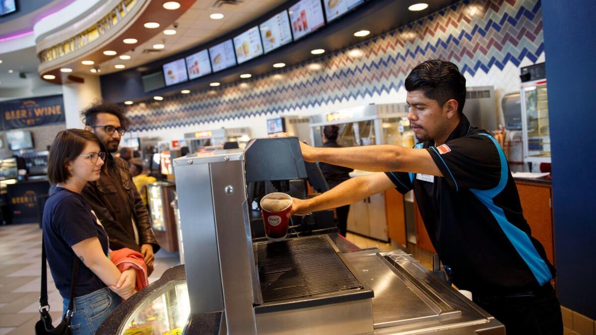An employee dispenses a soft drink for customers in the concessions area at the Regal Cinemas L.A. Live Stadium 14.