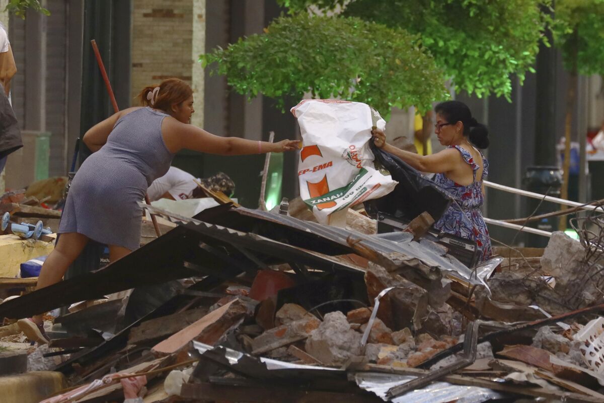 Personas rescatan pertenencias de entre los escombros de su vivienda derrumbadas 