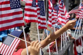 Los Angeles, CA - A child waves a flag while watching the Huntington Beach Independence Day Parade on July 4, 2023. Thousands of people gathered in the Orange County coastal community for the annual event. July 04: in Los Angeles on Tuesday, July 4, 2023 in Los Angeles, CA. (Luis Sinco / Los Angeles Times)