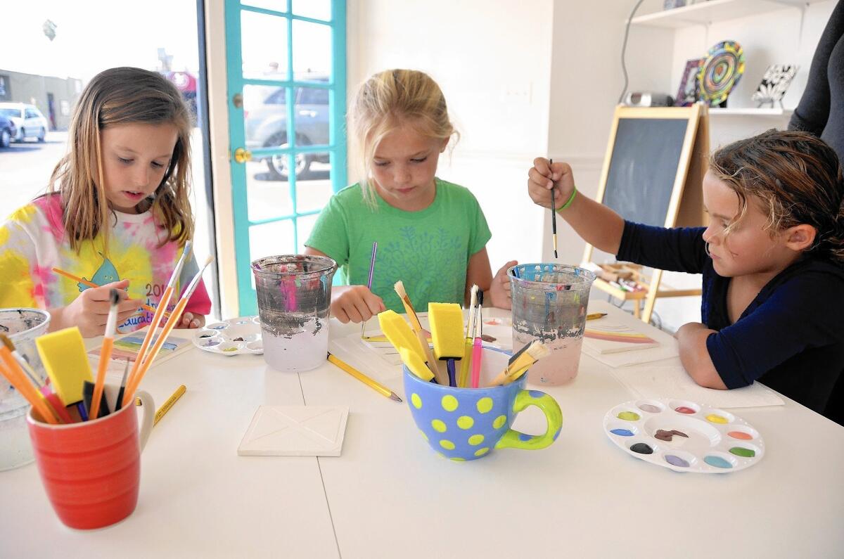 From left, Kirsten Brazelton, 10, Stella Boulton, 8, and Makena Haley, 7 apply colored glaze to tiles made of clay.