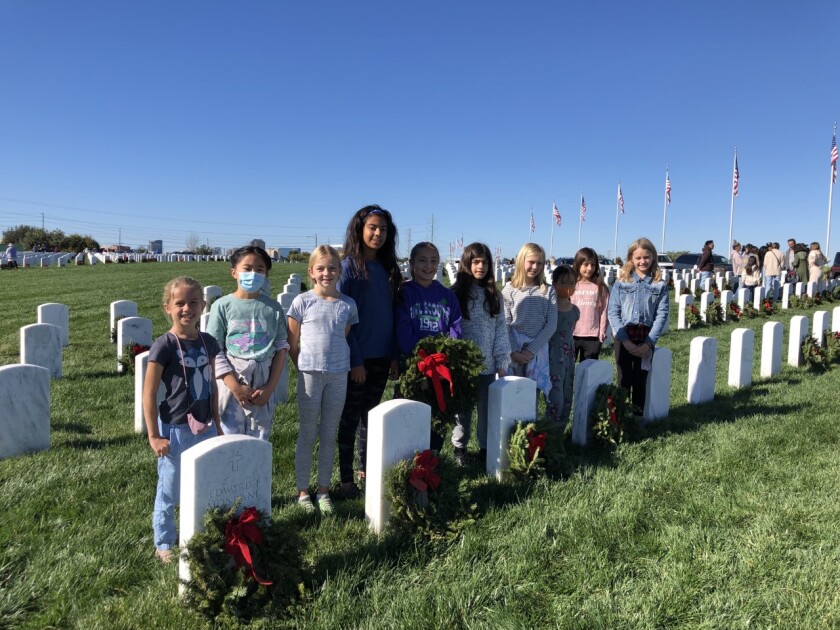 Girl Scout Troop 3925 members laying wreaths at Miramar National Cemetery for veterans.