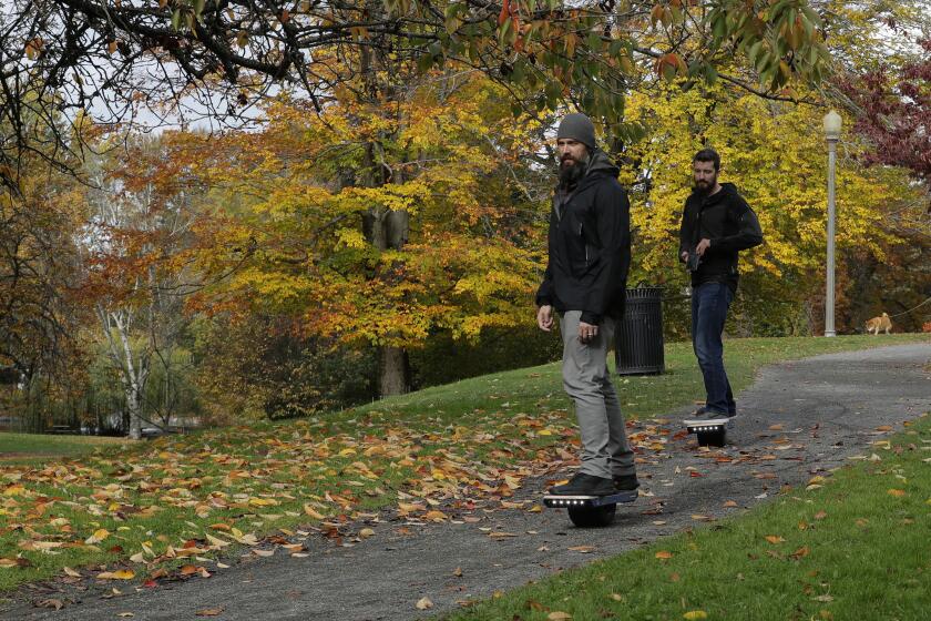 File - Two people ride Onewheels through Wright Park in Tacoma, Wash., on Oct. 26, 2018. All models of Onewheel self-balancing electric skateboards are under recall after at least four deaths and multiple injuries were reported in recent years, federal regulators said last week.(AP Photo/Ted S. Warren, File)