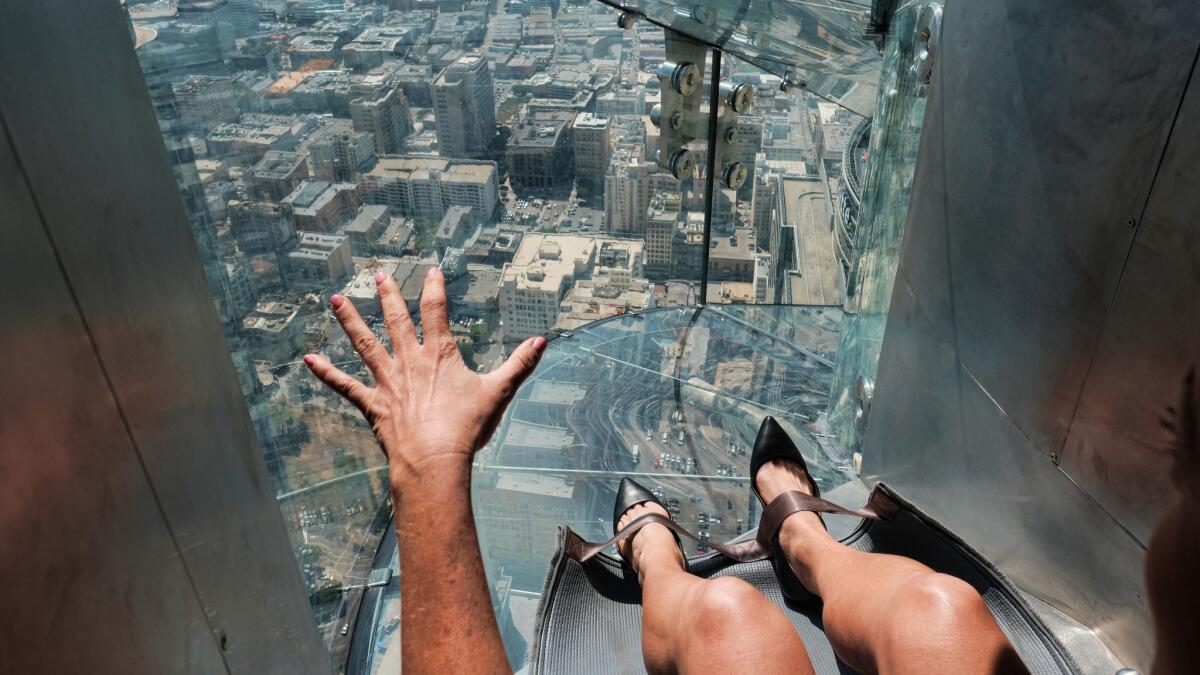 A member of the media prepares to take a ride down a glass slide at the U.S. Bank Tower on Thursday.