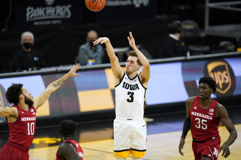 Iowa guard Jordan Bohannon (3) shoots a 3-point basket between Nebraska guard Kobe Webster, left, and center Eduardo Andre, right, during the first half of an NCAA college basketball game, Thursday, March 4, 2021, in Iowa City, Iowa. (AP Photo/Charlie Neibergall)