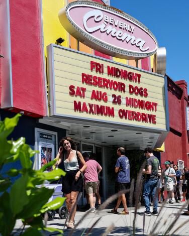 People line up outside the New Beverly Cinema on a sunny day.