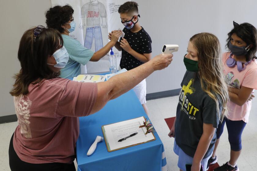 Science teachers Ann Darby, left, and Rosa Herrera check-in students at a school in Wylie, Texas.
