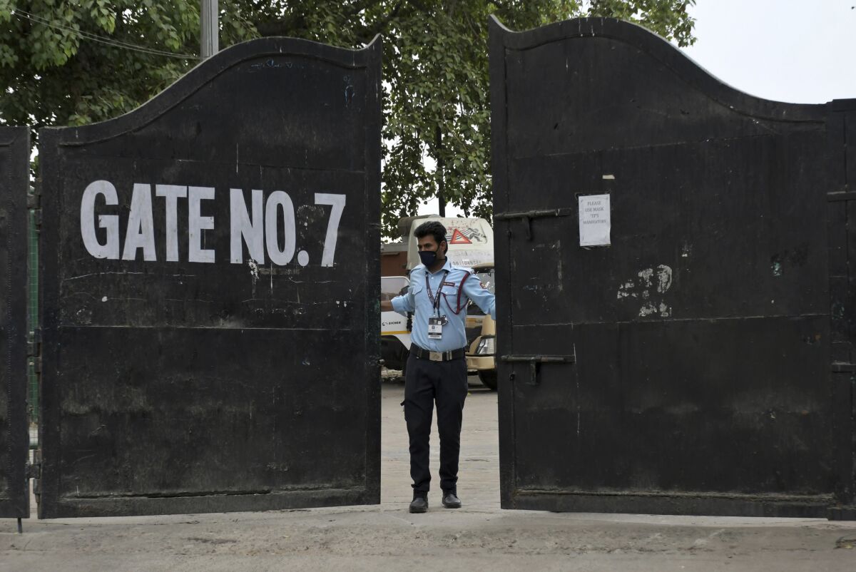 A security guard closes the gate of Arun Jaitley Stadium, one of the six venues of Indian Premier League 2021, in New Delhi, India, Tuesday, May 4, 2021. The Indian Premier League was suspended indefinitely on Tuesday after players or staff at three clubs tested positive for COVID-19 as nationwide infections surged. (AP Photo/Ishant Chauhan)