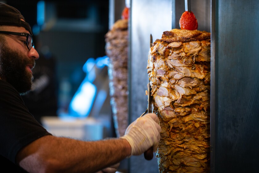 Mahmoud "Moody" Barkawi slices chicken shawarma at Tahini Street Food