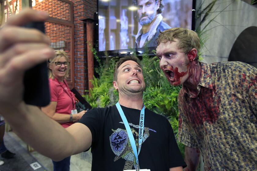 Josh Buonocore of Orlando , Florida, center, takes a selfie with a zombie at 'The Waliking Dead' Terminus wall at San Diego Comic-Con on July 23, 2014.