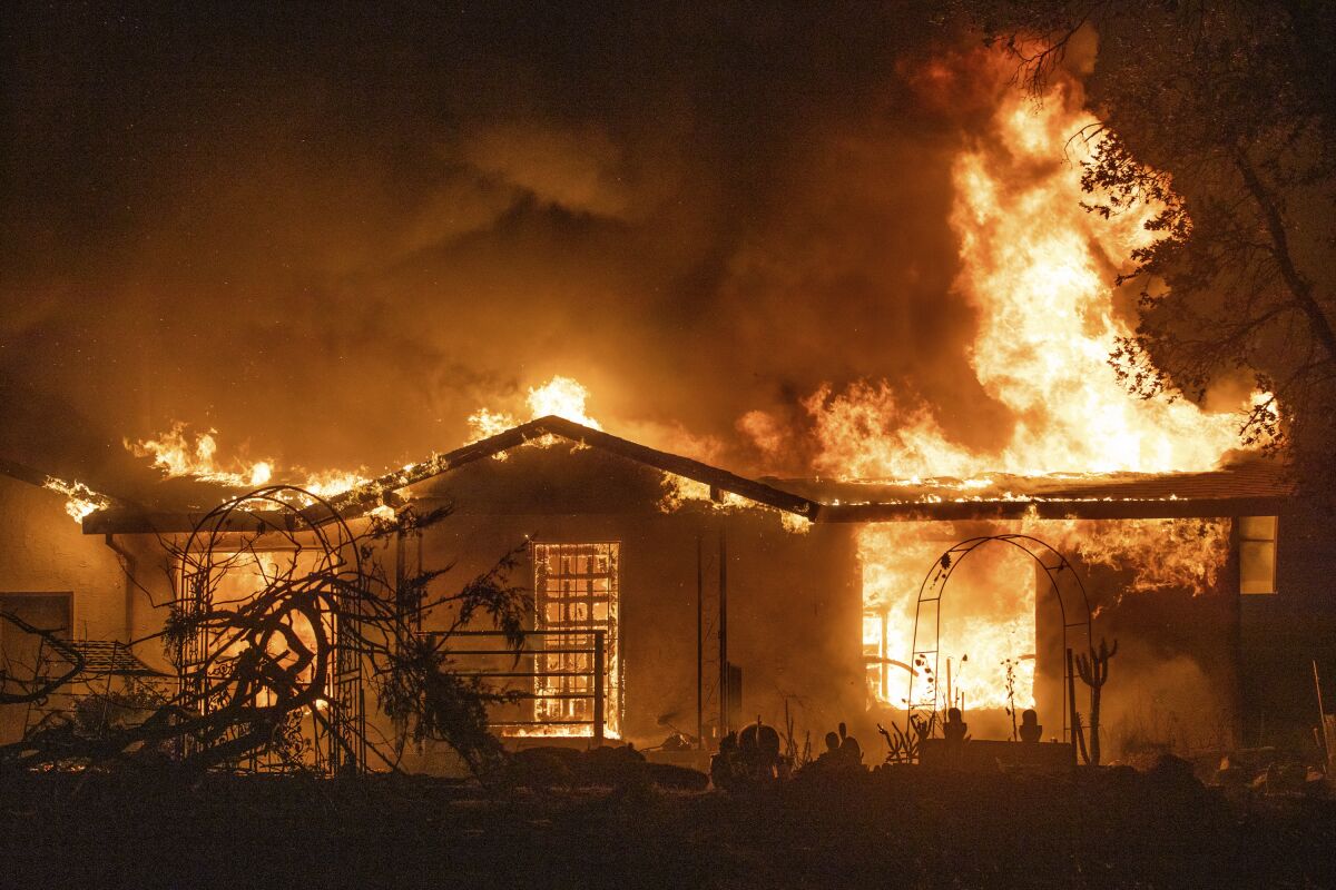 A burning house is fully engulfed in flames at night. 