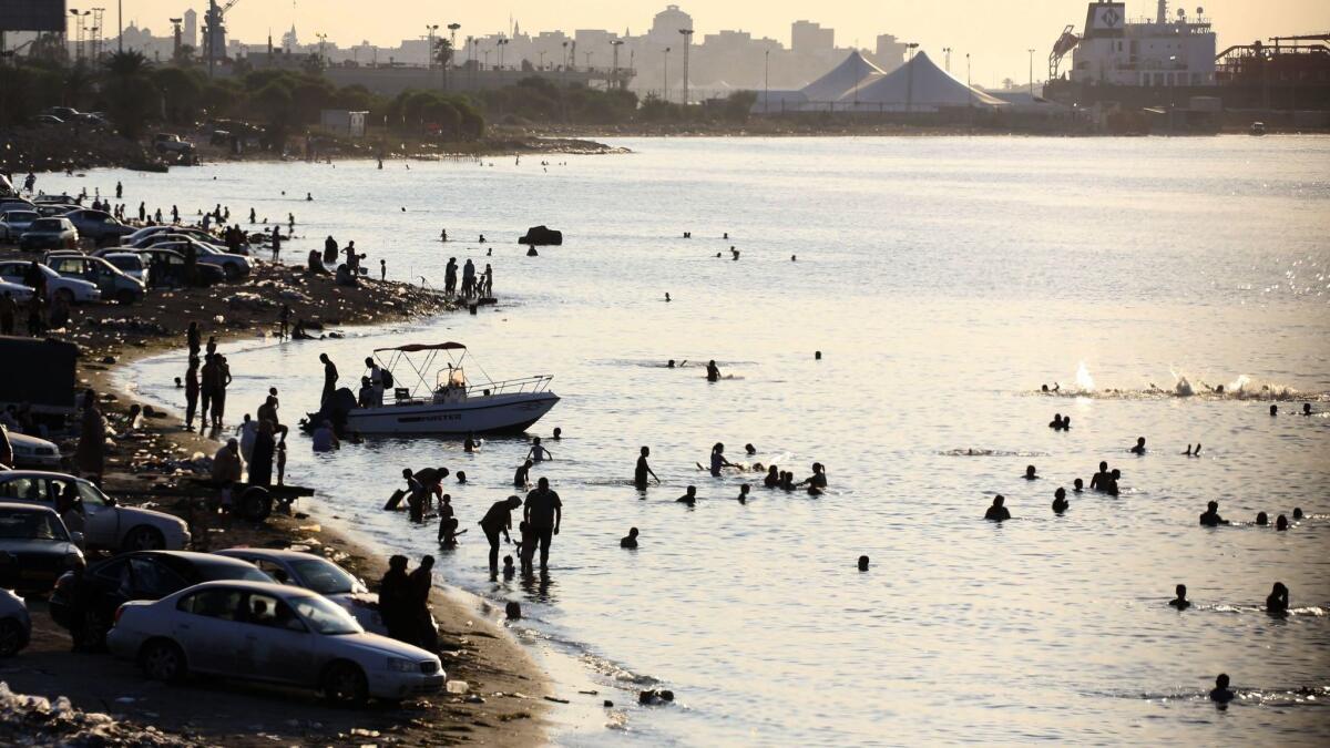 Libyans swim to cool off in the Mediterranean Sea in Tripoli, where power outages are frequent and daily hardships mount.