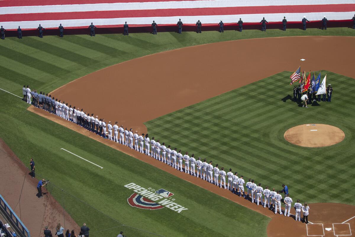 Dodgers players stand along the third-base line during the playing of the national anthem prior to the start of Thursday's game against the Arizona Diamondbacks.