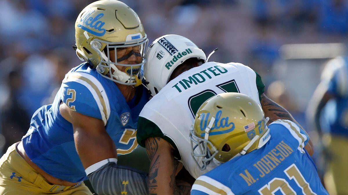 Hawaii wide receiver Kalakaua Timoteo, center, drops the ball and gets leveled by UCLA linebacker Josh Woods, left, and hit from behind by defensive back Mossi Johnson (21), during the second half on Sept. 9.