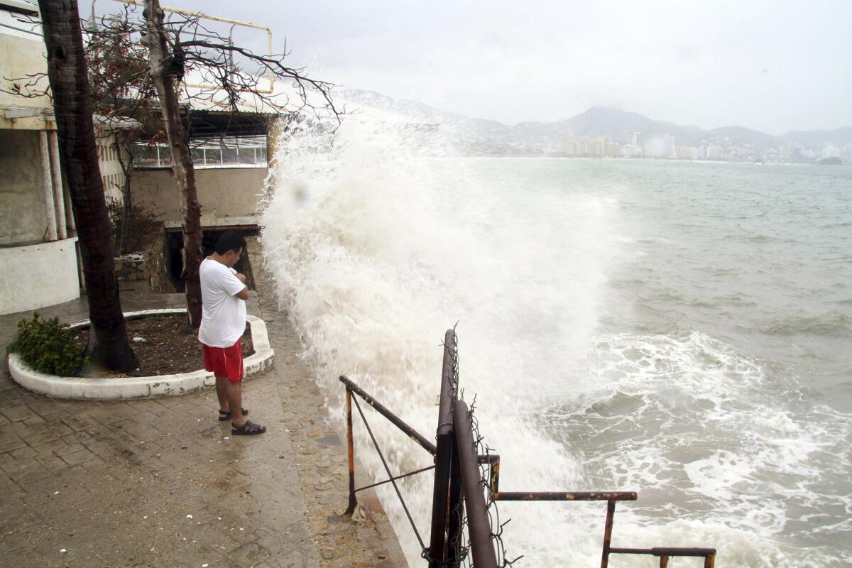 Un hombre observa las olas estrellarse contra un malecón en la localidad turística de Acapulco, México, el sábado 13 de junio de 2015. Las autoridades emitieron alertas para partes del suroeste de México ante los pronósticos de que el huracán Carlos se acerque a las costas el lunes en la tarde. (AP Foto/Bernandino Hernández)