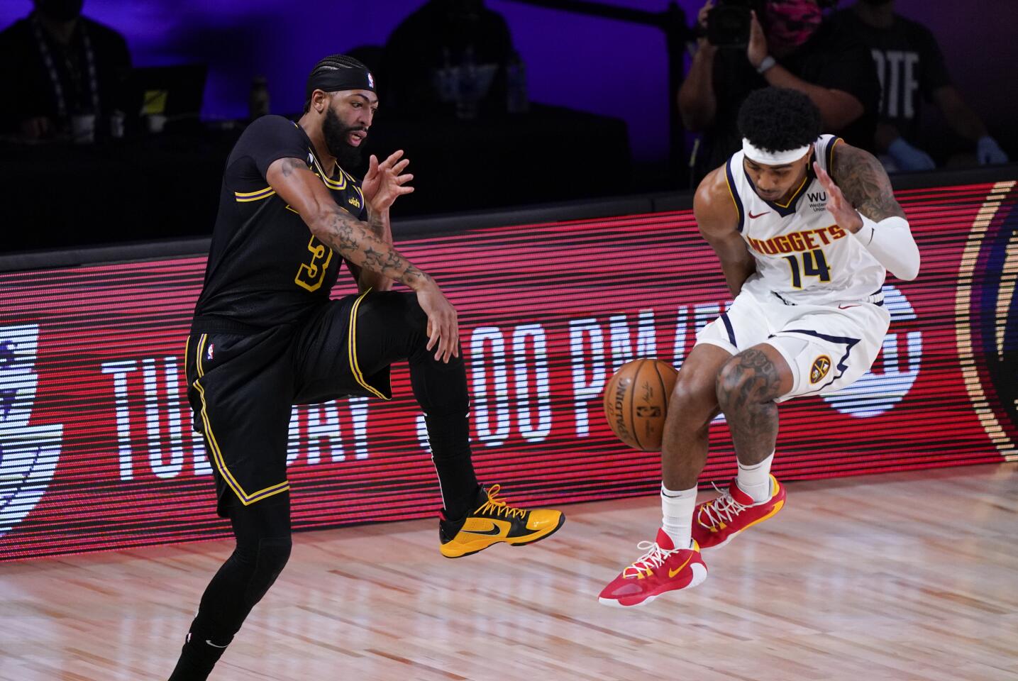 Lakers forward Anthony Davis saves the ball from going out of bounds by throwing it off Nugget guard Gary Harris.