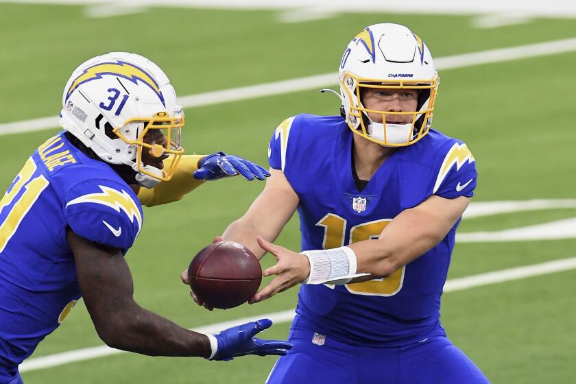 Los Angeles Chargers quarterback Justin Herbert (10) hands the ball off to running back Kalen Ballage.