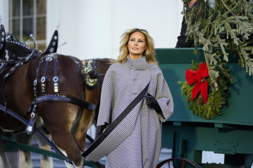 First lady Melania Trump stands next to the 2020 Official White House Christmas tree as it is presented on the North Portico of the White House, Monday, Nov. 23, 2020, in Washington. (AP Photo/Andrew Harnik)