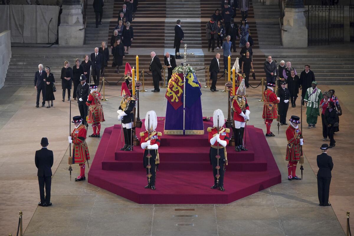 People file in to see the coffin of Queen Elizabeth II, surrounded by guards.