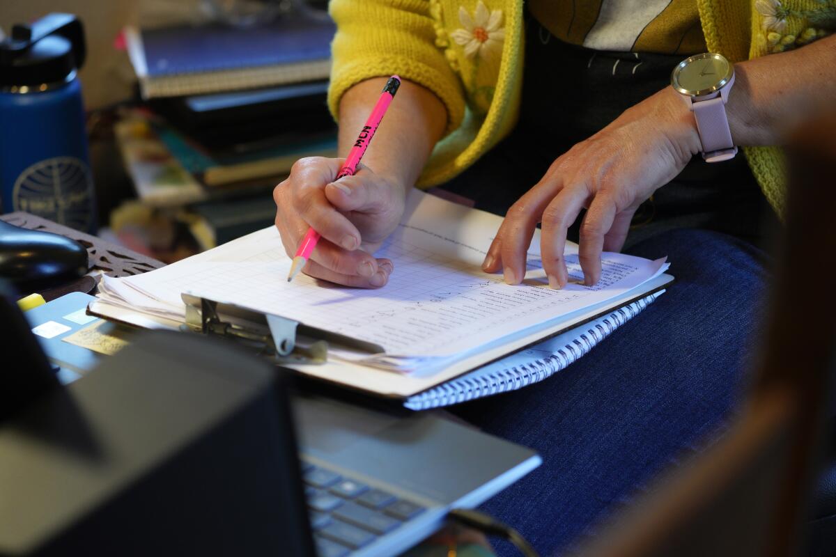 A teacher checks notes during a remote teaching session.