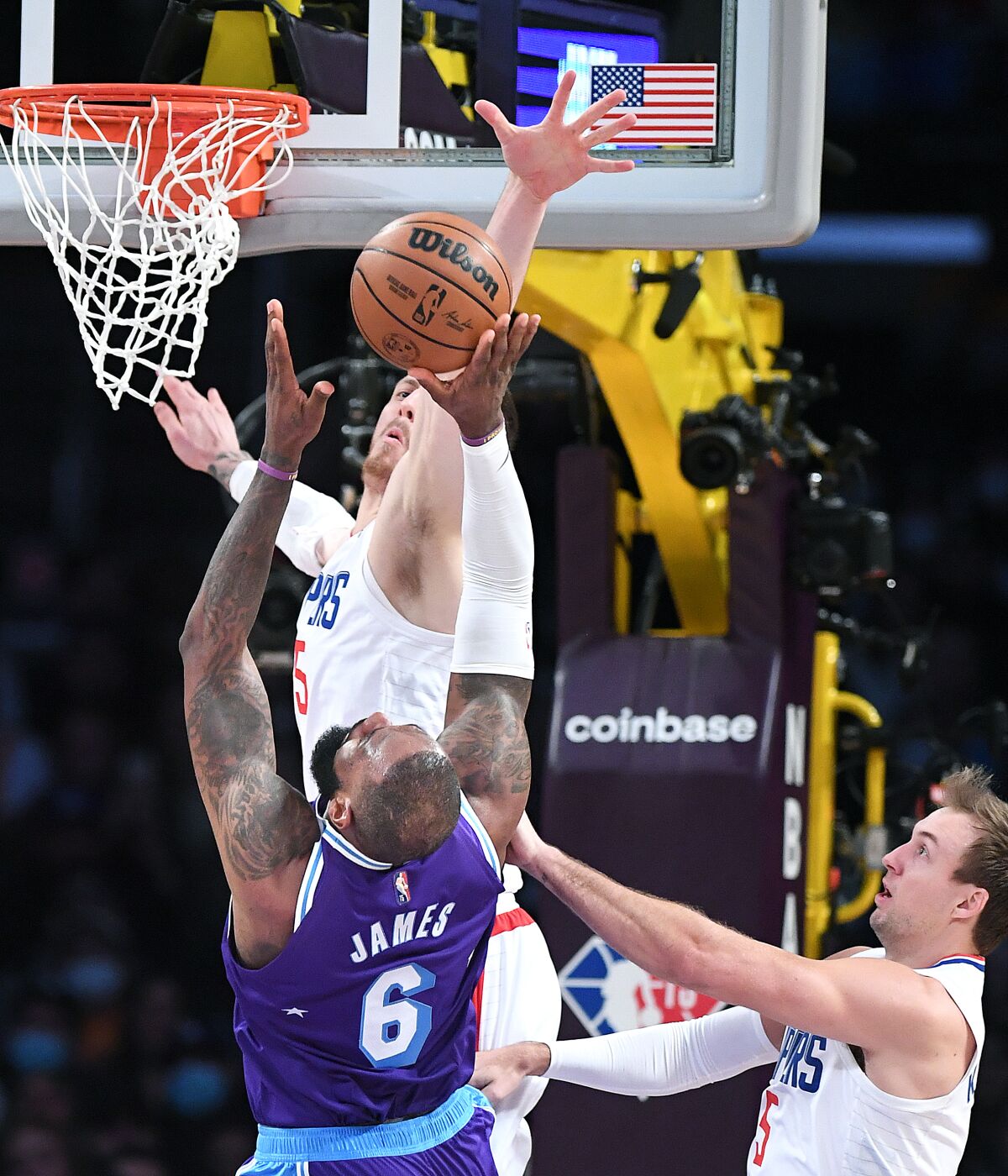 Lakers forward LeBron James attempts a layup while defended by Clippers guard Luke Kennard and center Isaiah Hartenstein.