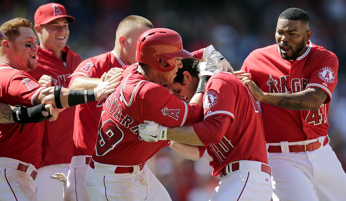 Angels shortstop Grant Green (10) is swarmed by teammates after driving in the winning run against the Mariners with two out in the ninth inning Sunday at Angel Stadium.