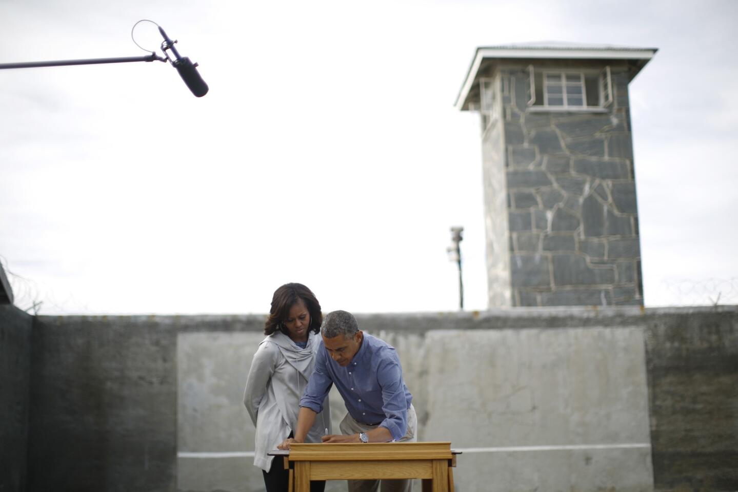 U.S. President Obama writes in a guest book as he tours Robben Island with the First lady near Cape Town