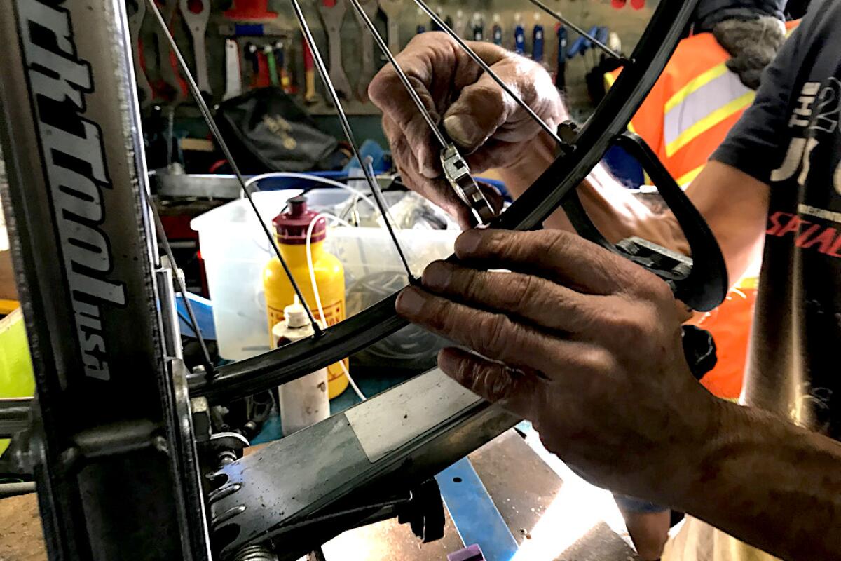 A closeup of hands working on a bicycle wheel