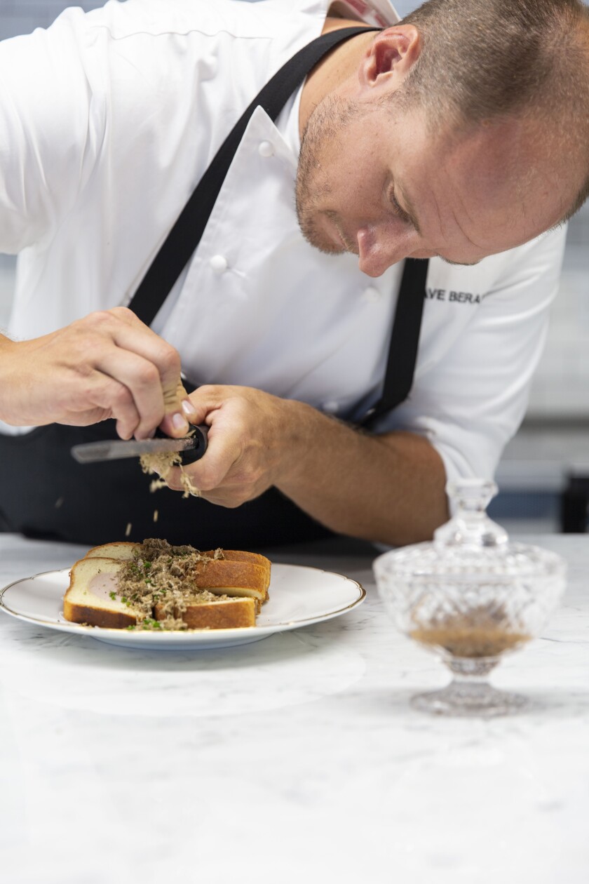 A photo of chef Dave Beran shaving fresh truffle over foie gras toast at Pasjoli.