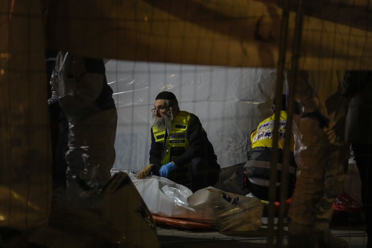 Members of Zaka Rescue and Recovery team check victims of a shooting attack near a synagogue in Jerusalem, Friday, Jan. 27, 2023. A Palestinian gunman opened fire outside an east Jerusalem synagogue Friday night, killing seven people, including a 70-year-old woman, and wounding three others before police shot and killed him, officials said. It was the deadliest attack on Israelis in years and raised the likelihood of further bloodshed. (AP Photo/Maya Alleruzzo)