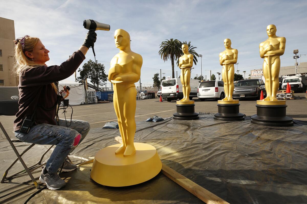 Dena D’Angelo aims a hairdryer at the head of a freshly painted Oscar statue.