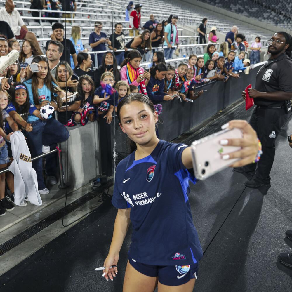 A woman taking a selfie with fans