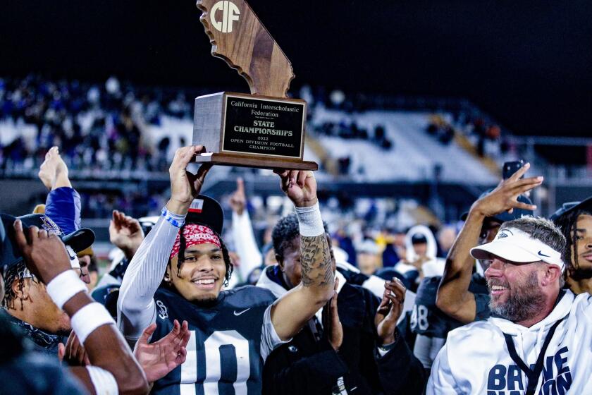 St. John Bosco quarterback Pierce Clarkson holds up state championship trophy as coach Jason Negro celebrates.