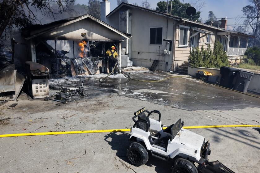 CORONA, CA - JUNE 24: A firefighter works on putting out flames in a garage that caught fire at the Serrano Fire on Monday, June 24, 2024 in Corona, CA.(Gina Ferazzi / Los Angeles Times)