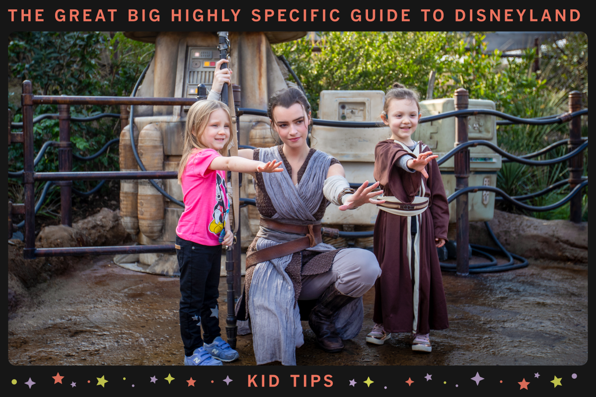 A Disneyland cast member dressed as Star Wars hero Rey crouches between two young girls.