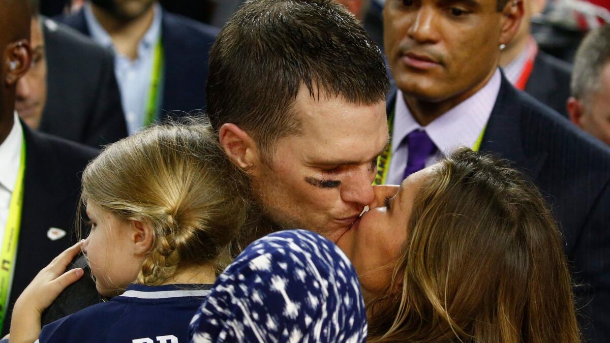 New England Patriots quarterback Tom Brady kisses his wife, Gisele Bundchen, while holding daughter Vivian Lake Brady after Super Bowl LI.