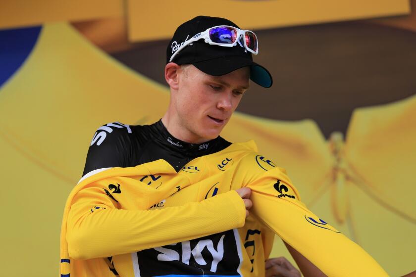 Chris Froome puts on the overall race leader's yellow jersey after winning Stage 8 of the Tour de France on Saturday.