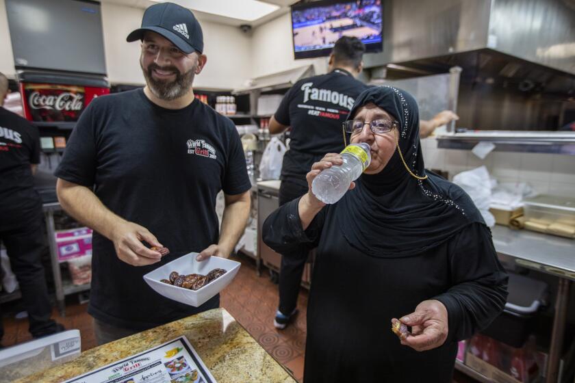BELL, CA - APRIL 09: Ali Telfi, left, and his mother Zeinab Telfi, right, are breaking their fast at their families resteraunt at World Famous Grill on Saturday, April 9, 2022 in Bell, CA. Ali and Zeinab are fasting during Ramadan and are working around food all day. In the evening they break their fast with a prayer, eating a date, and drinking water. (Francine Orr / Los Angeles Times)