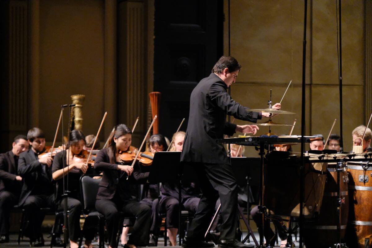 Violinists follow the baton of conductor Carlos Izcaray during an American Youth Symphony performance at UCLA's Royce Hall.