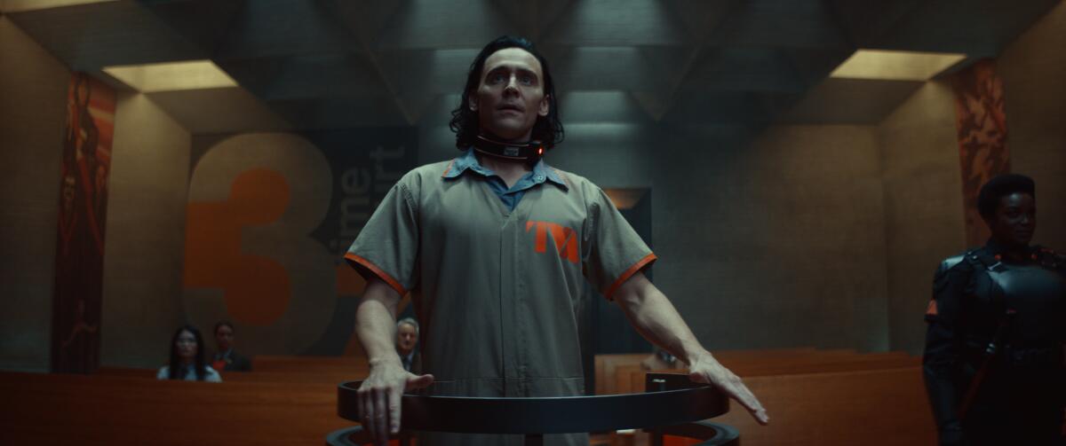 A man in a jumpsuit stands in a futuristic courtroom