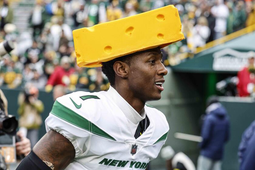 New York Jets cornerback Sauce Gardner (1) wears a cheesehead as he reacts after beating the Green Bay Packers.