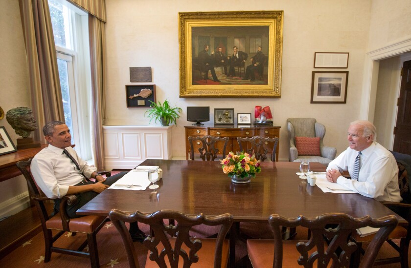 President Obama and Vice President Joe Biden are smiling at a White House dinner table.