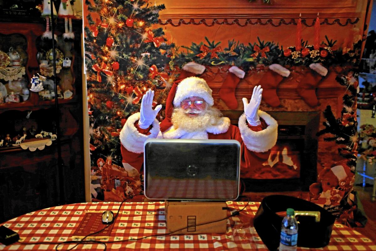 Ed Taylor, dressed as Santa,  smiles as he does a virtual St. Nick visit on his computer.