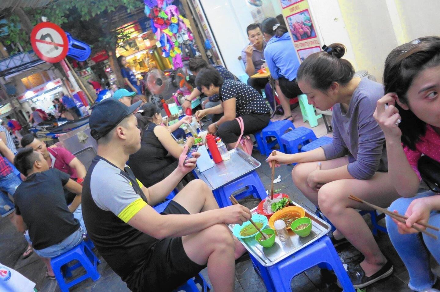 Sidewalk dining on small blue chairs is a hallmark of life in Hanoi.