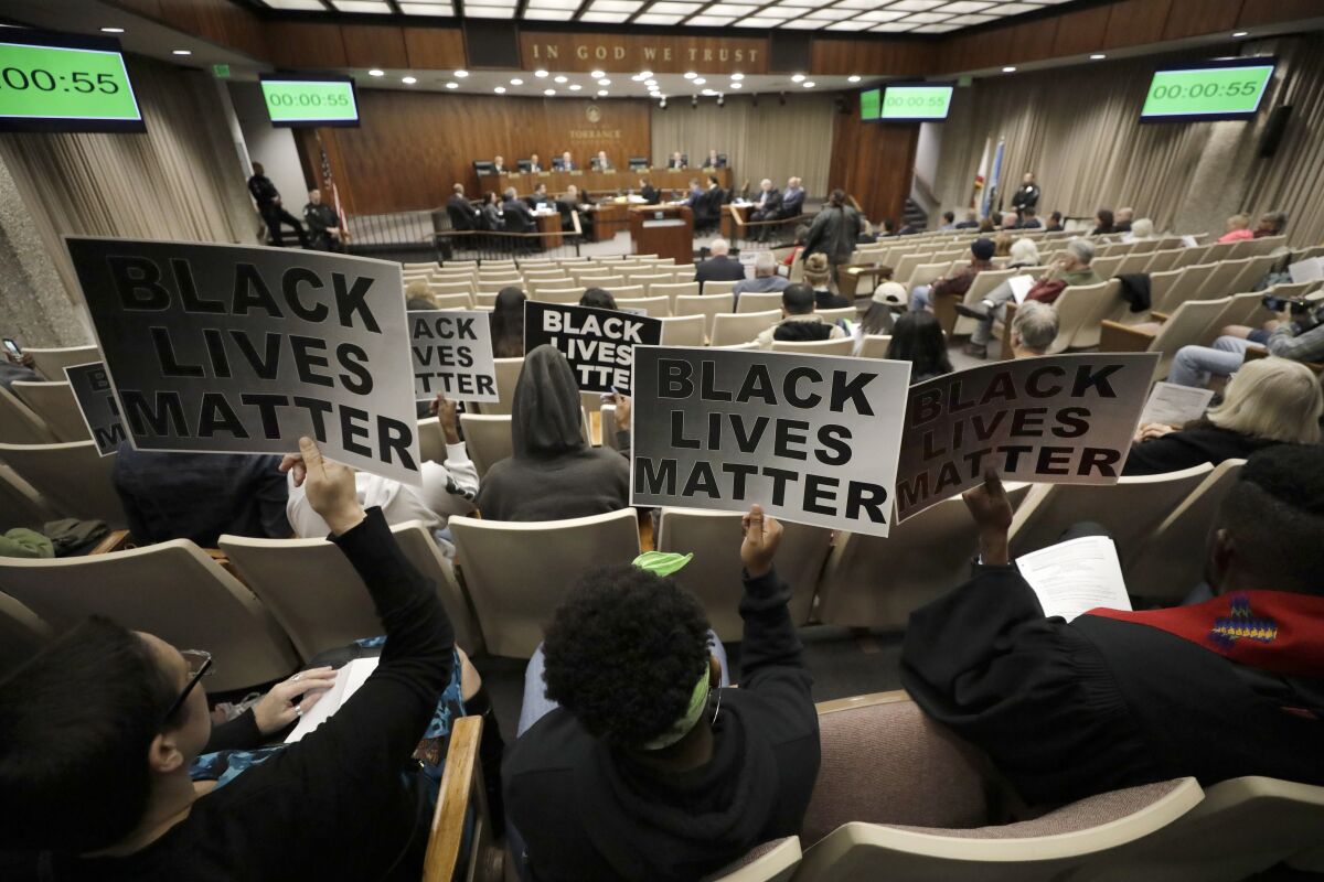 Protesters with "Black Lives Matter" signs attend a city council meeting